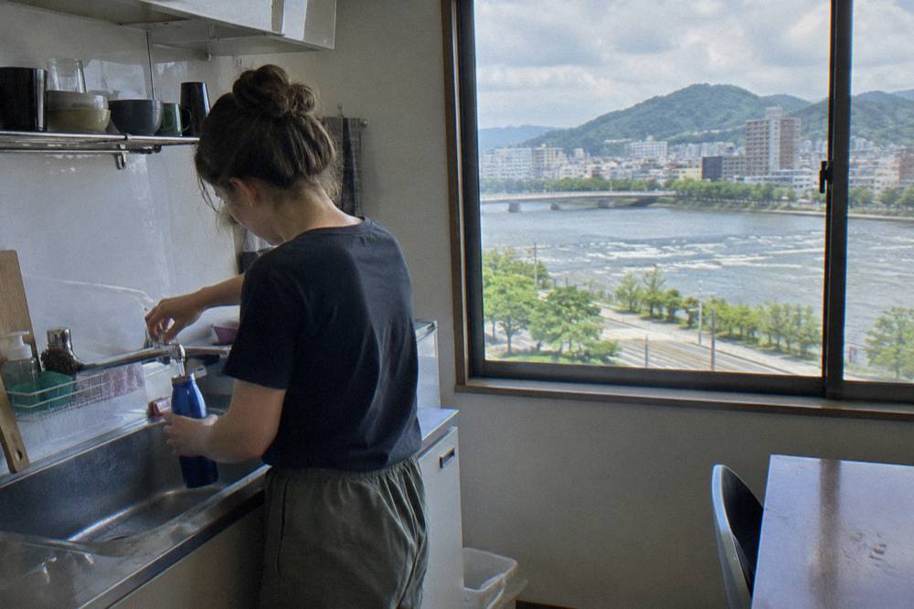 A traveller filling a reusable water bottle from a tap in a Hiroshima accommodation