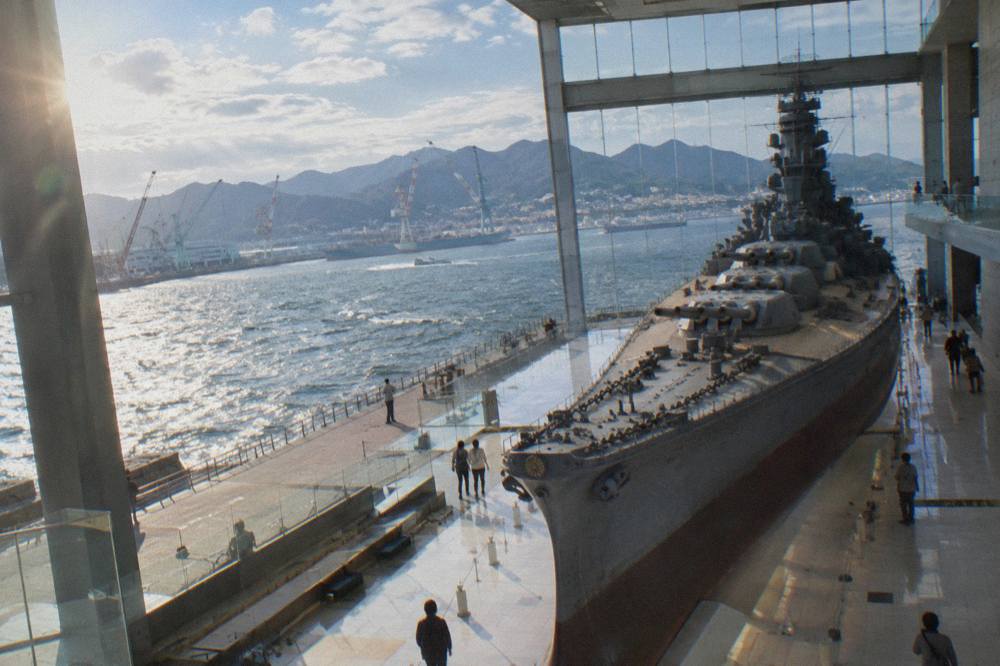 A harbor view from a museum terrace with shipyards and port cranes along the water