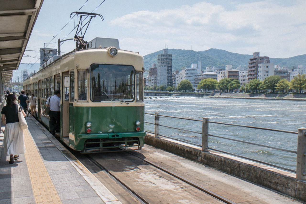 A Hiroden streetcar stopped at a downtown Hiroshima stop with passengers boarding