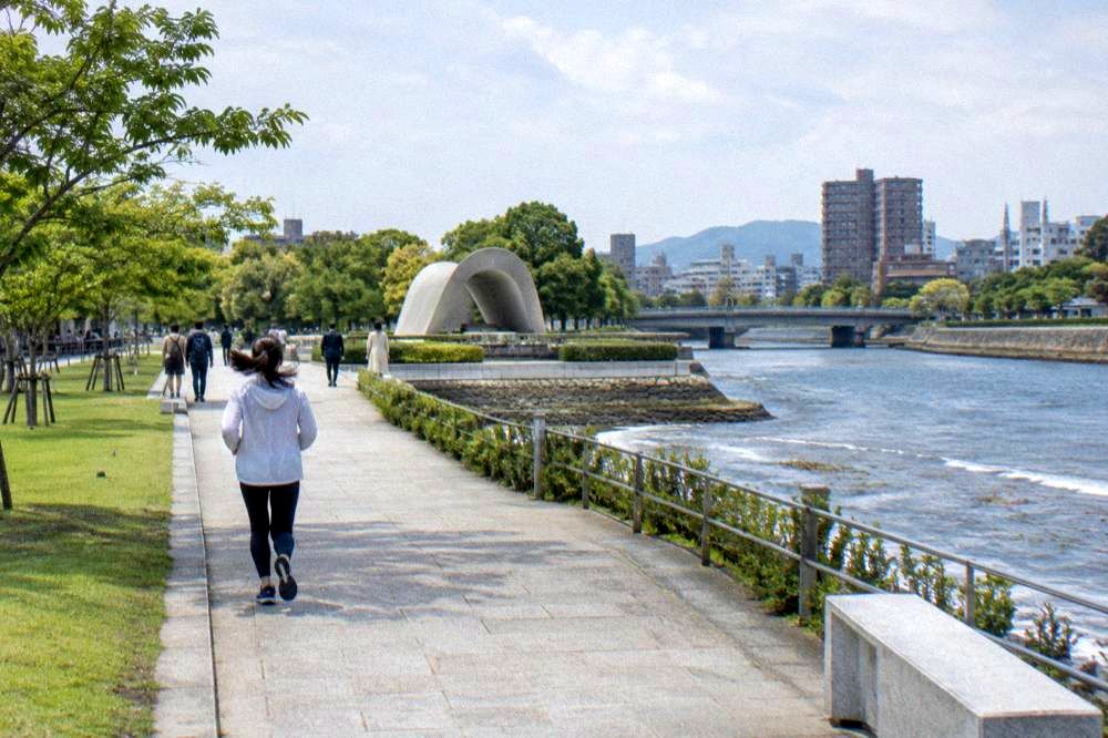 Visitors walking quietly along the paths of Peace Memorial Park in Hiroshima near the cenotaph