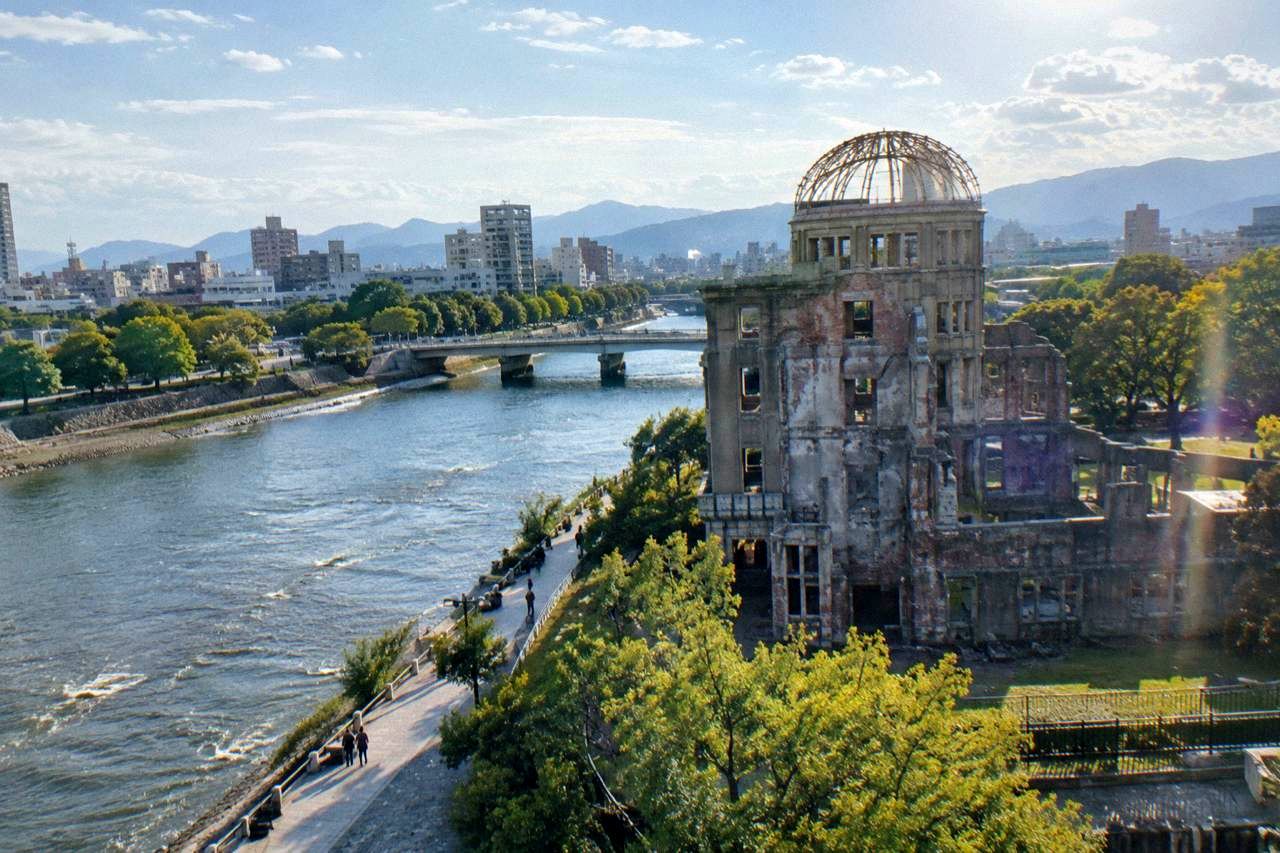 The A-Bomb Dome in Hiroshima standing beside the Ota River under a calm sky