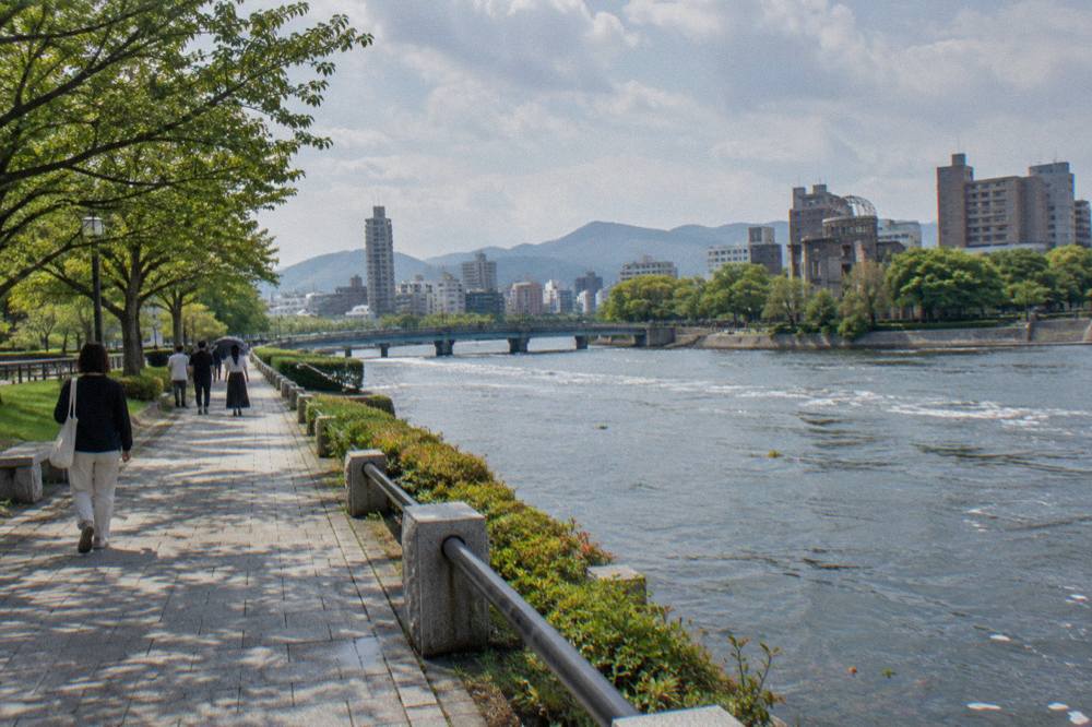 Visitors walking quietly along a tree-lined path in the Hiroshima Peace Memorial Park