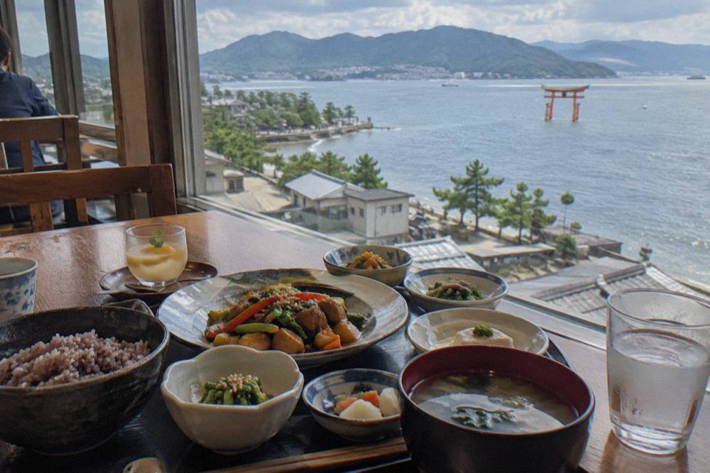 A vegan seven-course Chinese meal set out on a table beside a window overlooking Miyajima's coastline