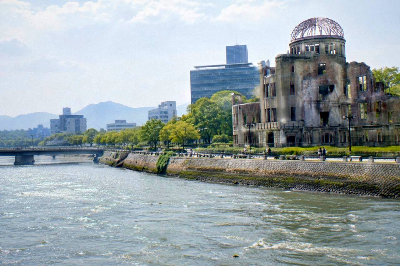 The Peace Memorial Park in Hiroshima with green lawns, the A-Bomb Dome across the river, and modern city buildings behind it