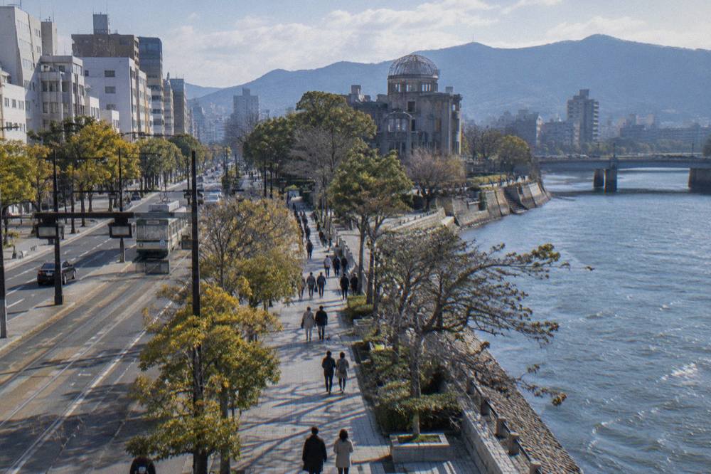Pedestrians strolling beside the Aioi Street roadway toward the Atomic Bomb Dome in Hiroshima