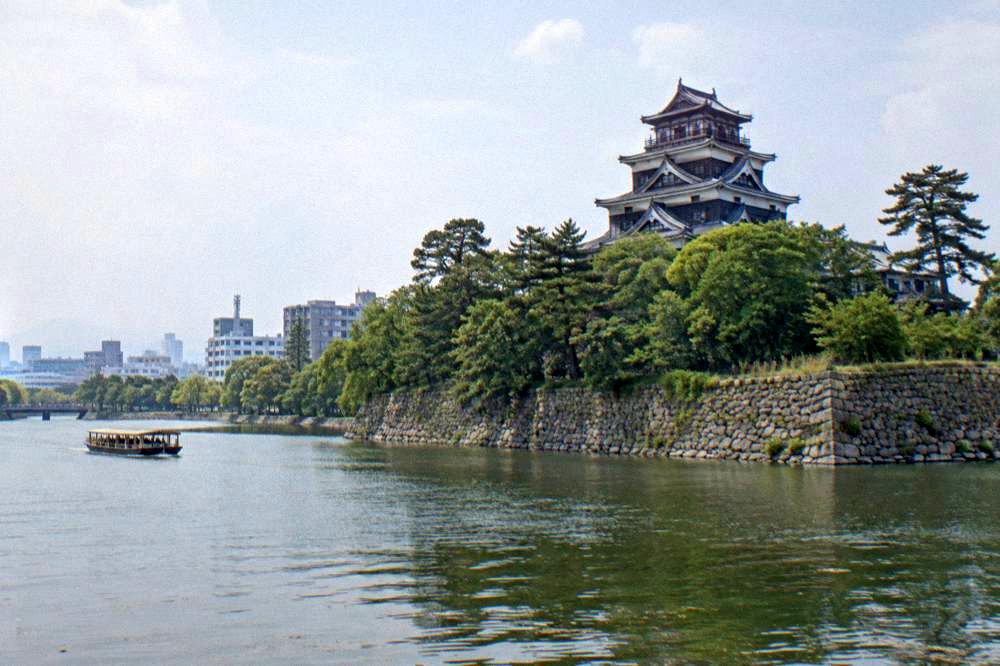 Hiroshima Castle stone walls and moat with the keep roof above the trees