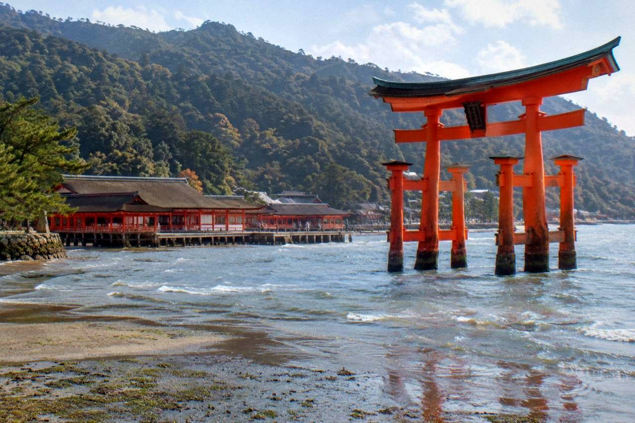 The Great Torii of Itsukushima Shrine standing in Hiroshima Bay at low tide with the shrine buildings behind it