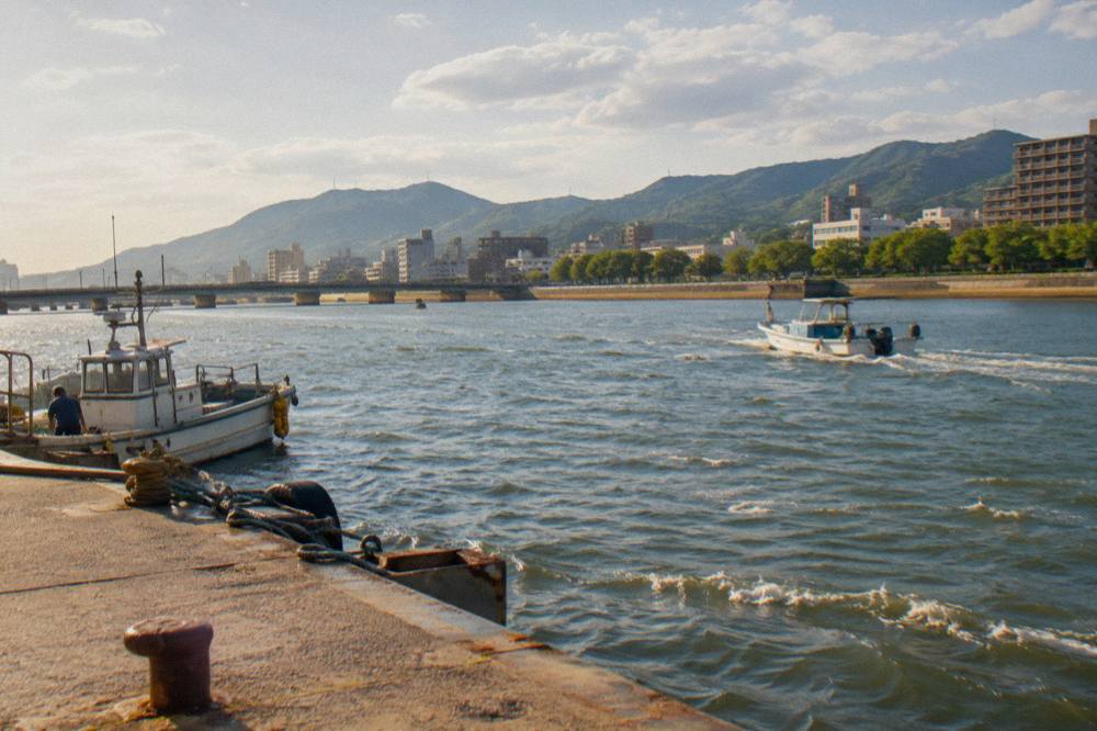 A calm bay dotted with small islands under a bright sky, seen from a coastal city