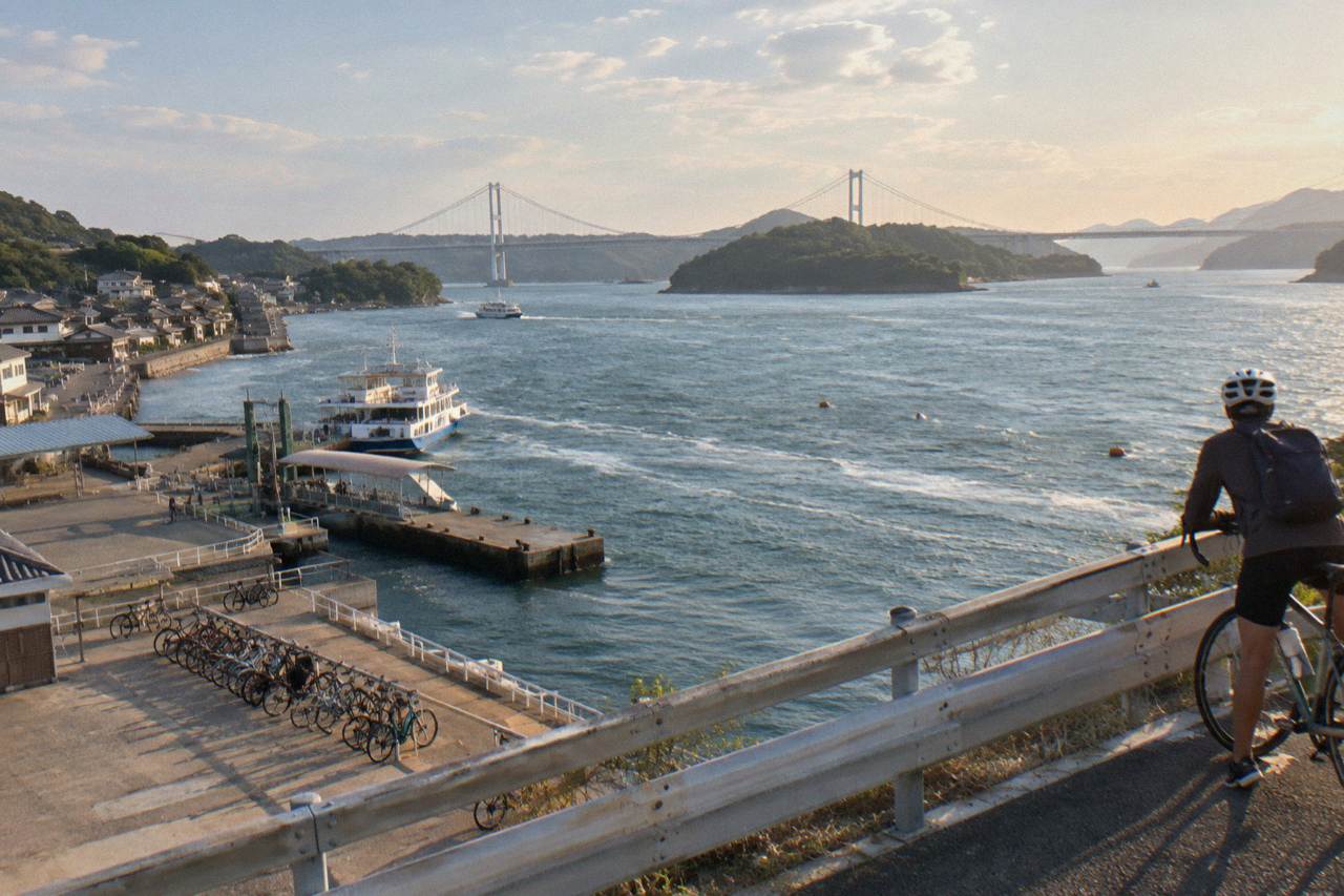 A cyclist pausing on a bridge over the Seto Inland Sea with green islands below