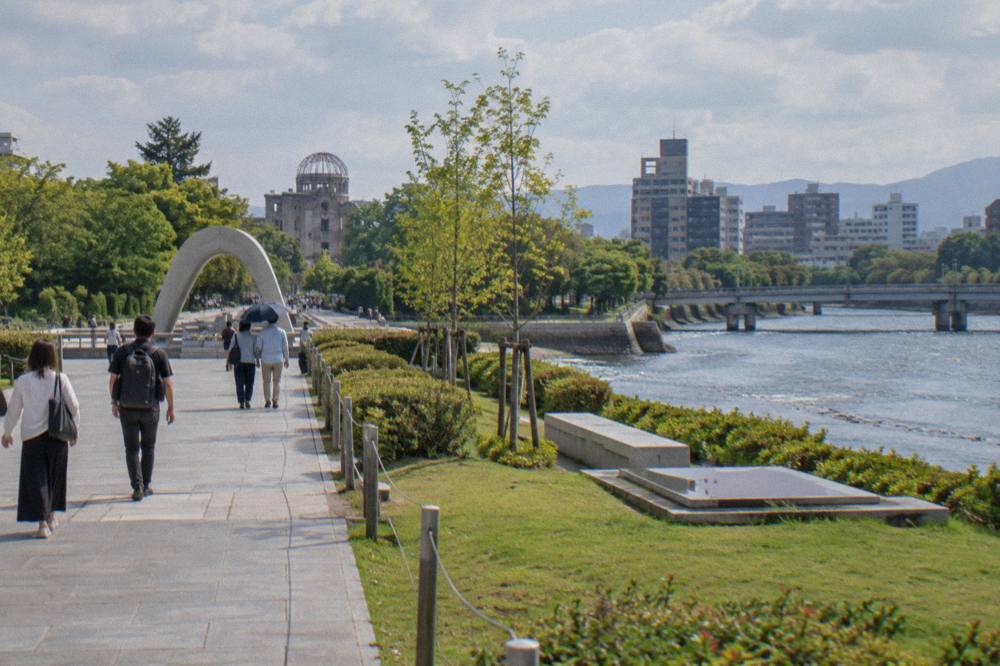 Visitors walking along a peaceful path in Hiroshima Peace Memorial Park toward the Cenotaph