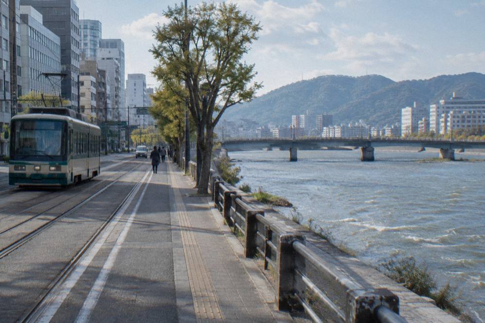 A quiet street of modern buildings and tram tracks in central Hiroshima under a clear sky