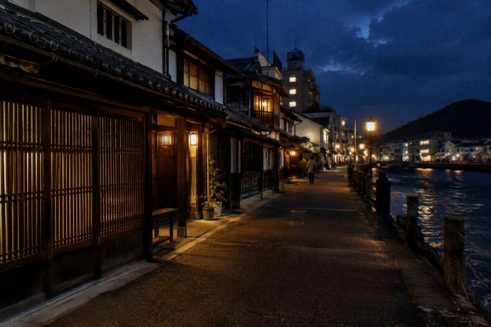 Empty lane at night with old timber houses lit by warm string lights
