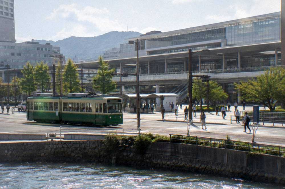 A Hiroden green streetcar passing through a central Hiroshima street