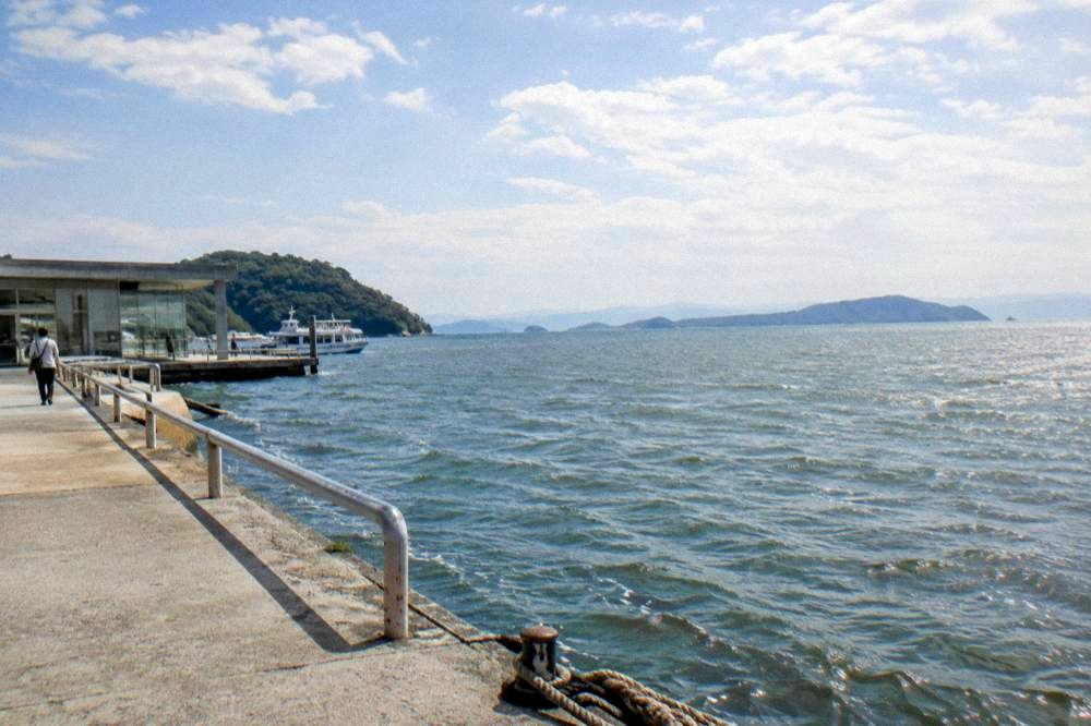 View across Hiroshima Bay from a waterfront promenade with islands on the horizon