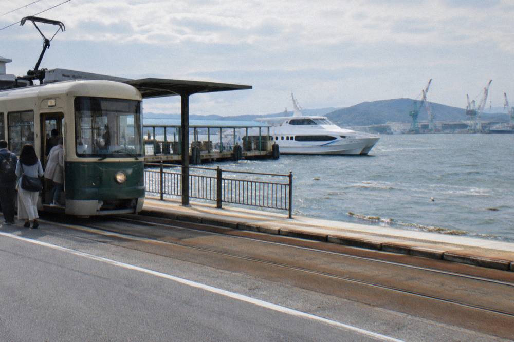 Hiroden streetcar at a stop near the port with passengers boarding