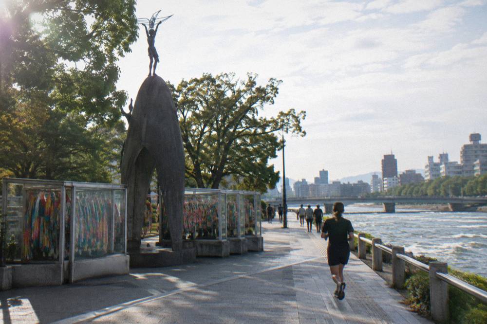 Glass cases filled with colorful strings of folded paper cranes beside the monument