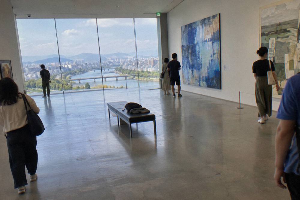 Gallery visitors looking at large contemporary paintings in a bright museum hall