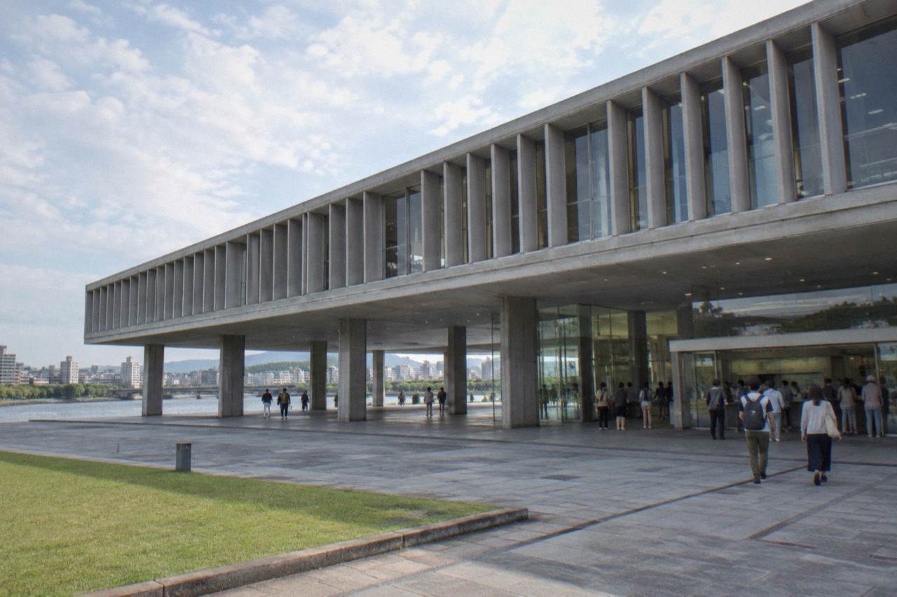 The modern concrete entrance hall of a peace museum with visitors gathering at the ticket counter