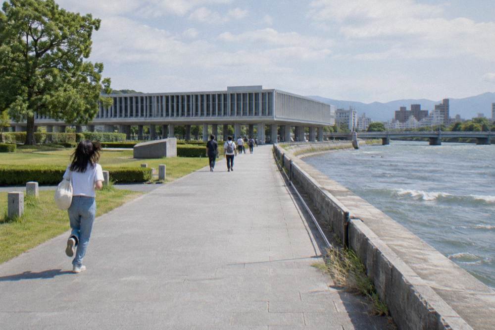 Visitors walking quietly along a park path lined with lawns and memorial monuments