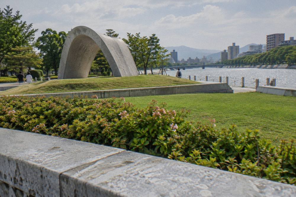 Saddled stone arch monument resting on a low mound in a lawn park with trees
