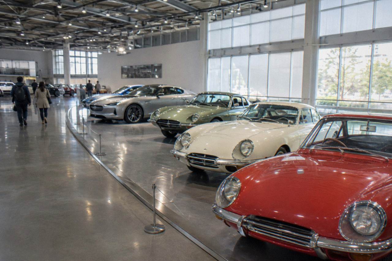 Classic and modern cars displayed on a bright museum floor in a car factory museum hall