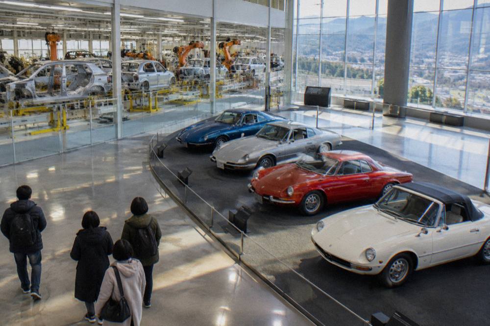 A display of classic Mazda sports cars arranged in a curved row inside the museum