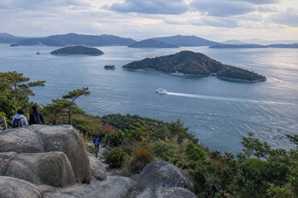 White passenger ferry crossing calm water toward a forested island