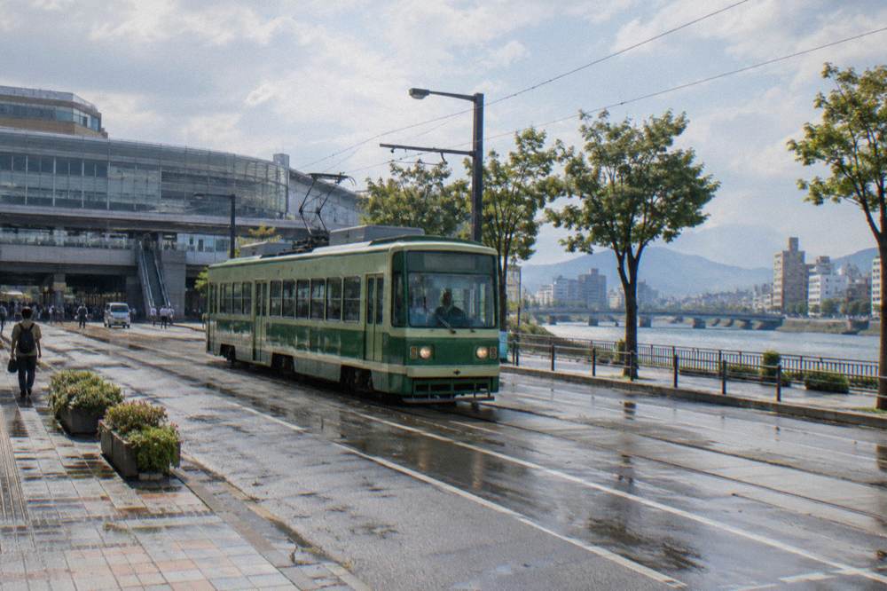 A Hiroden green tram moving along a street in central Hiroshima