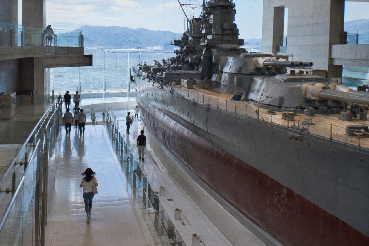 A large scale model of a battleship displayed in a bright museum atrium