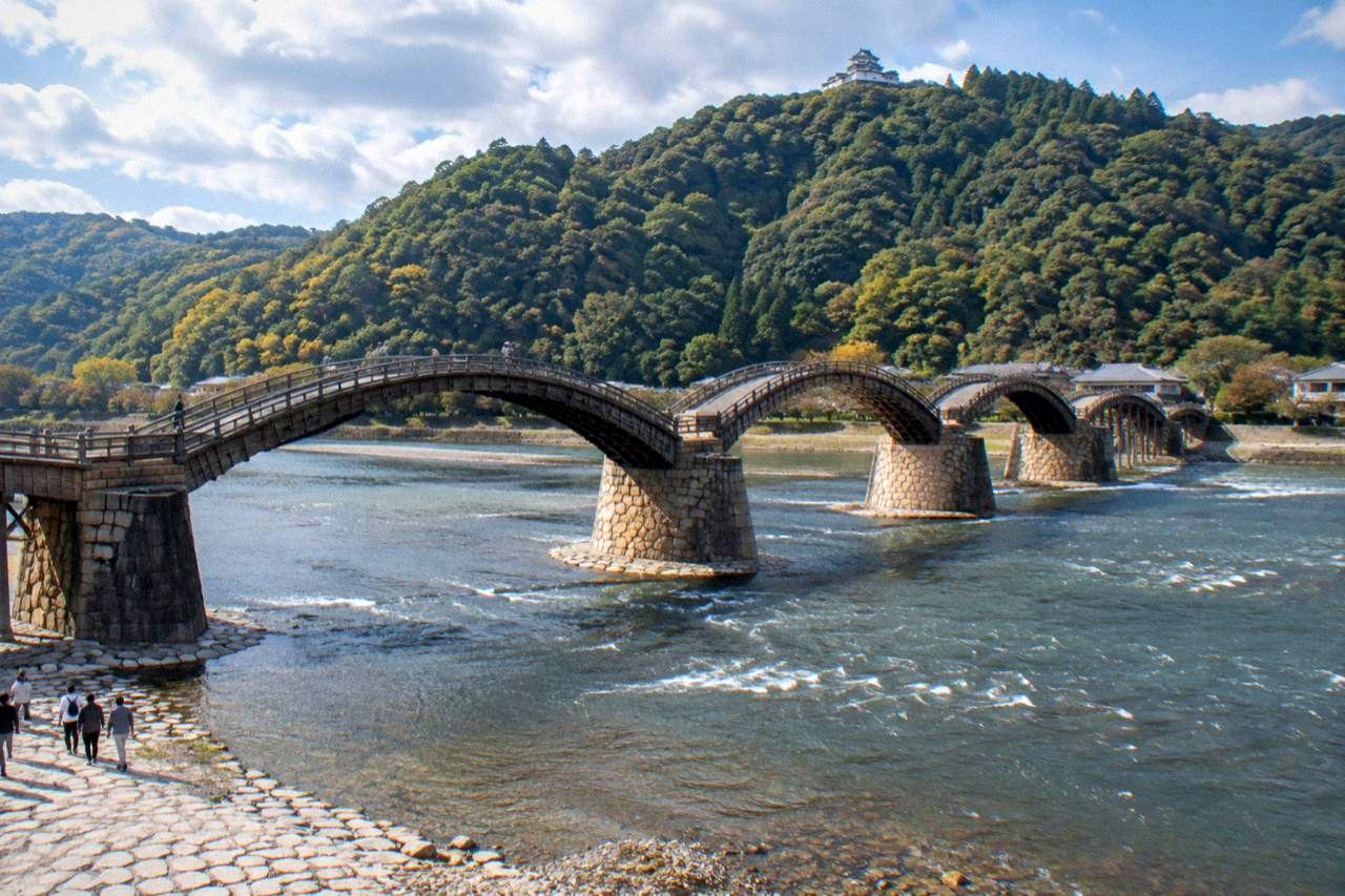 Five wooden arches of Kintaikyo Bridge crossing the Nishiki River with forested hills behind