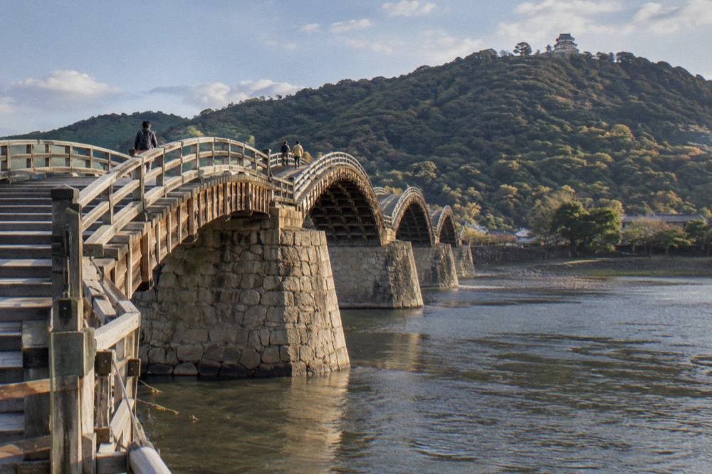 Close view of the stepped wooden deck and arches of Kintaikyo Bridge over calm water