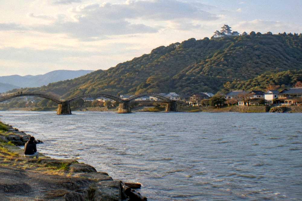 White castle keep on a forested hillside above a river valley