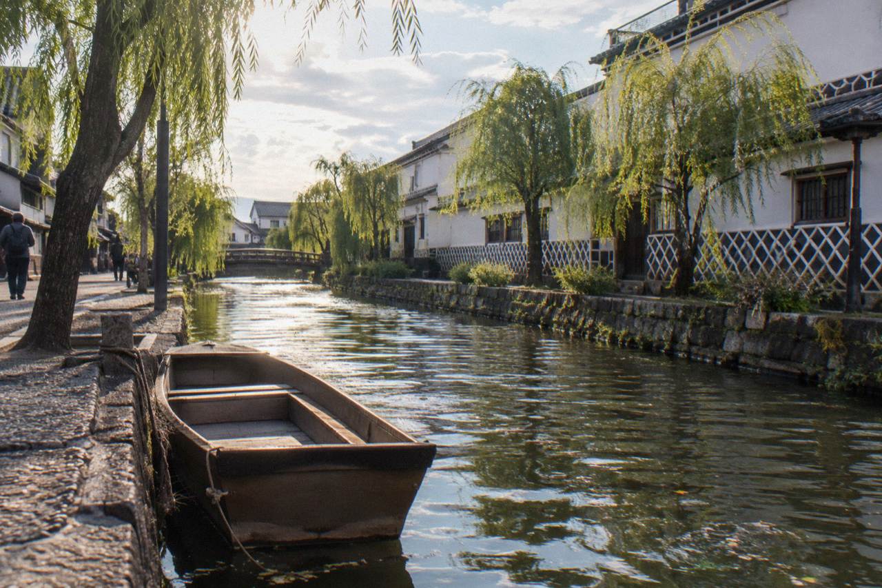 Kurashiki Bikan Historical Quarter with white walled storehouses along a willow lined canal