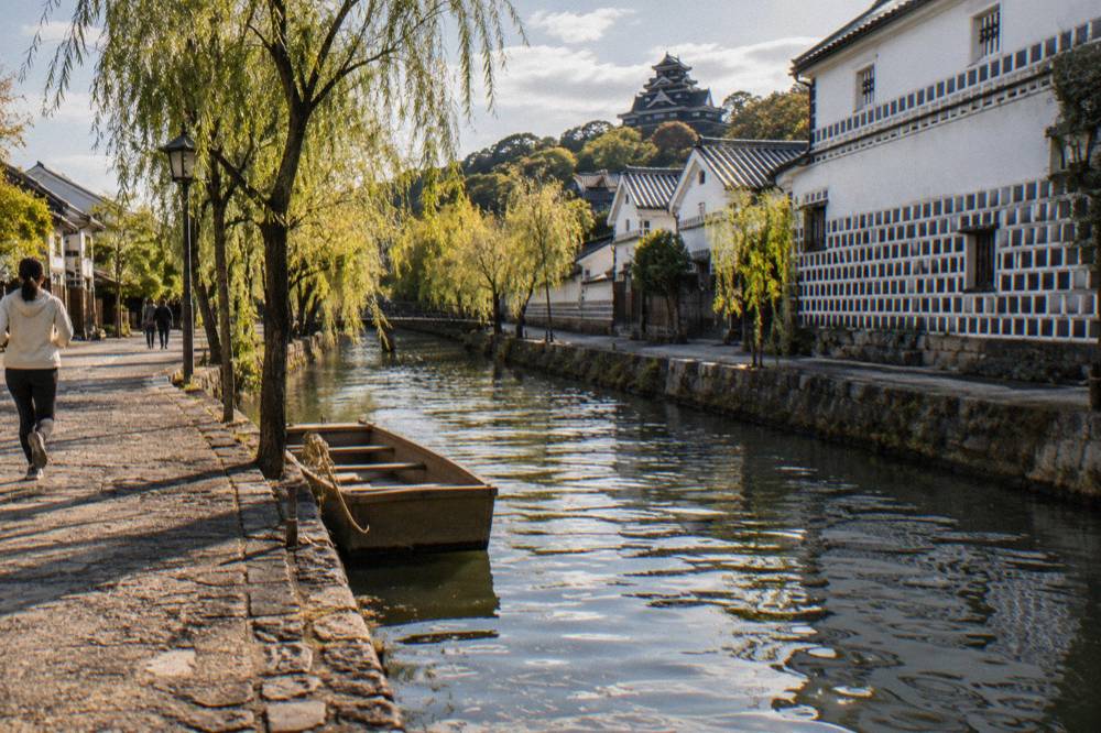 A black exterior Japanese castle keep reflected in water at Okayama