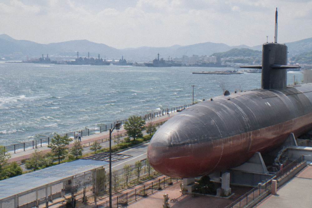 The bow section of a retired submarine displayed outside a museum building in Kure