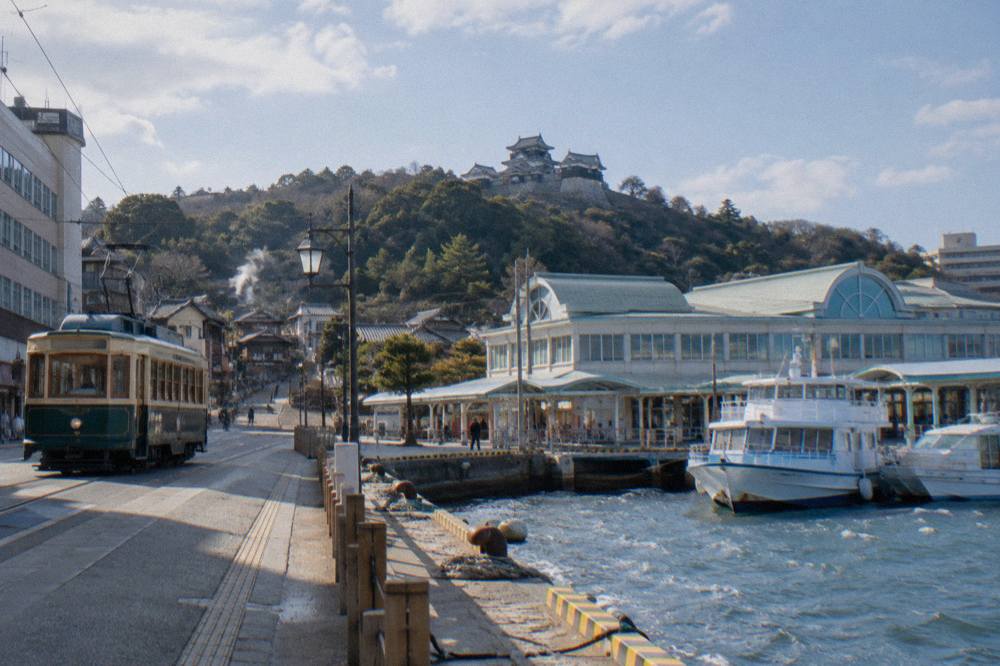A passenger ferry terminal building with boats moored at a quay in the late afternoon