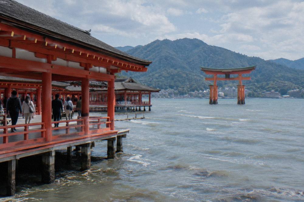 Visitors walking the wooden corridors of Itsukushima Shrine above the water