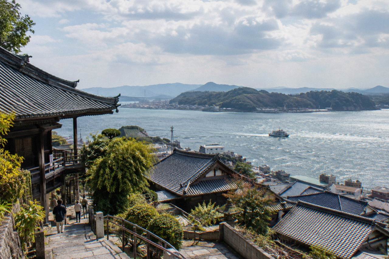 Hillside temple rooftops above the Onomichi Channel with the Seto Inland Sea beyond