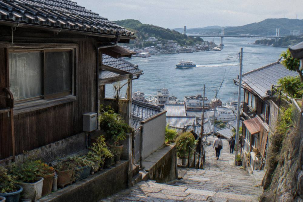 A narrow stone-paved lane climbing between wooden houses in Onomichi