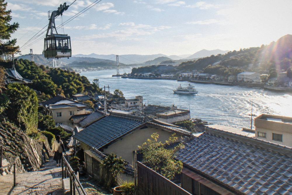 A cable car cabin on a hillside ropeway line above Onomichi rooftops