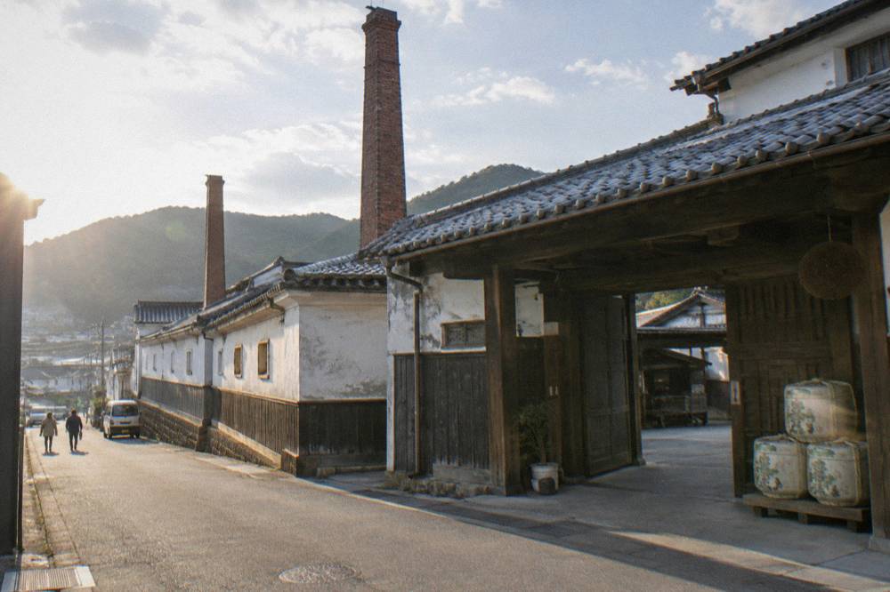 A wooden brewery entrance with sake barrels stacked beside the door