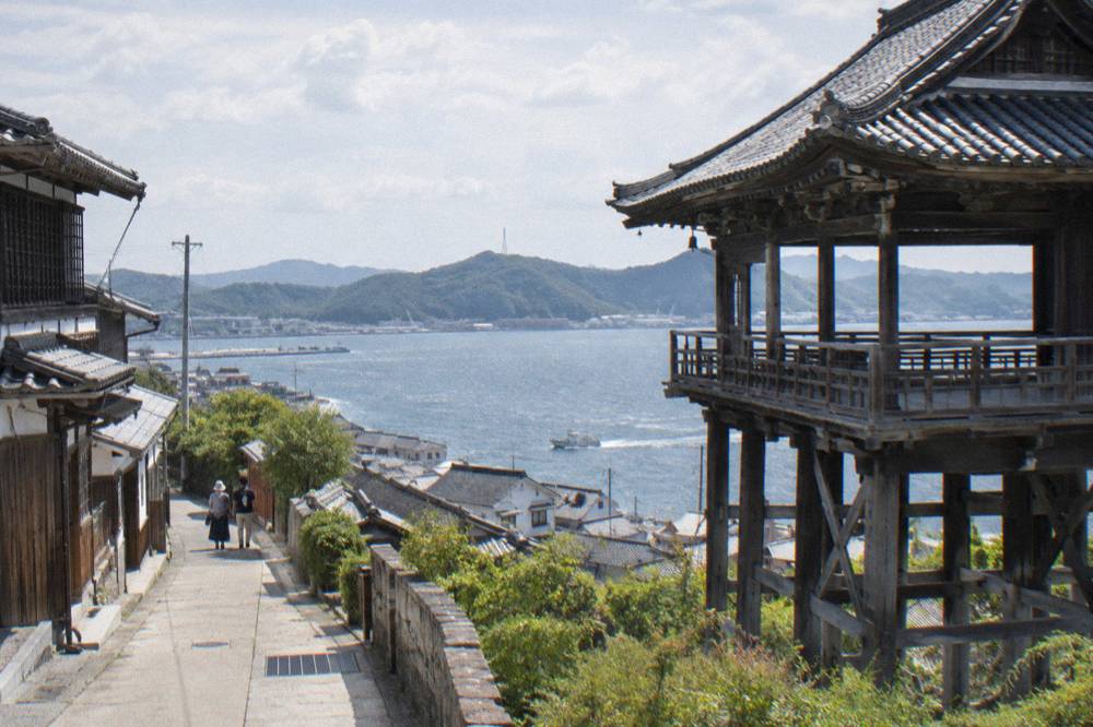 A wooden temple pavilion built out on stilts above a hillside town