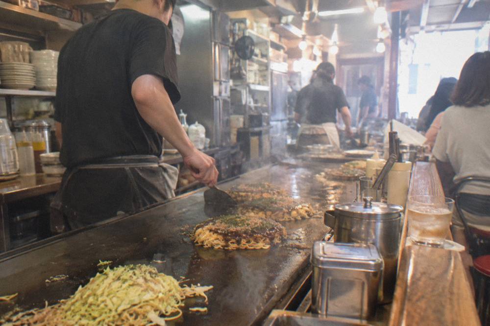 An okonomiyaki restaurant floor inside Okonomimura with counters and griddles