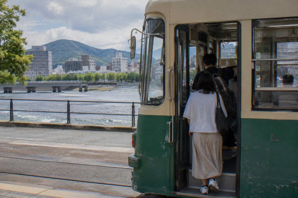 Passengers boarding a Hiroden tram at a street stop in central Hiroshima