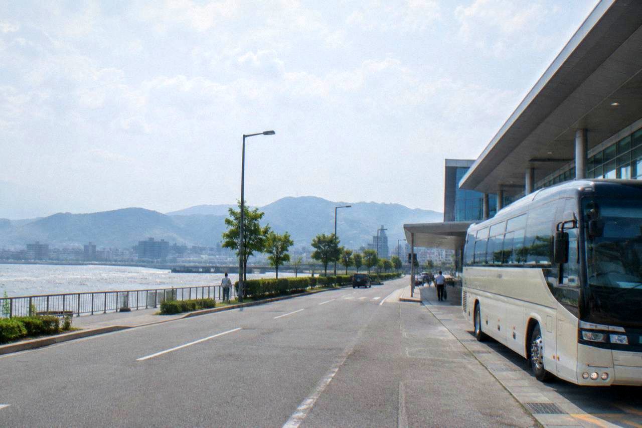 A limousine bus parked at the curb outside a modern airport terminal building in daylight