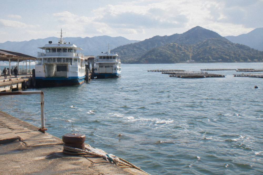 Ferries moored at Miyajimaguchi pier with the island and hills across the water