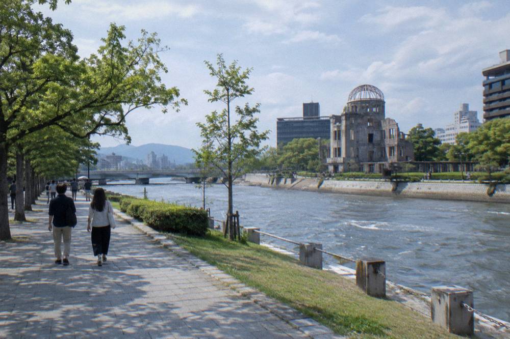 Visitors walking quietly along a tree-lined path in Hiroshima Peace Memorial Park