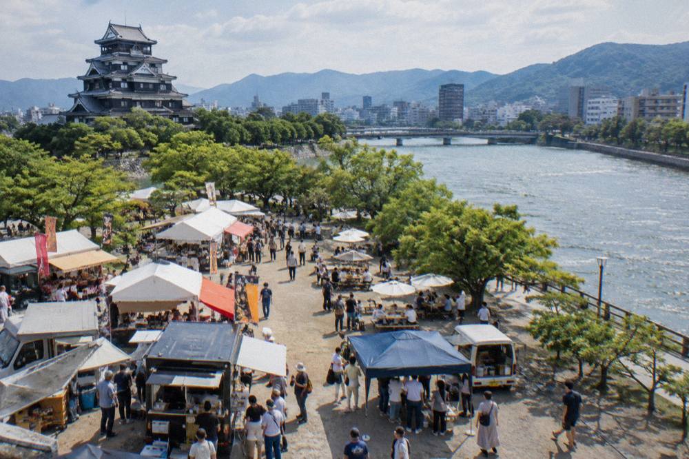 Food stalls and visitors at an outdoor food festival in a castle square in Japan