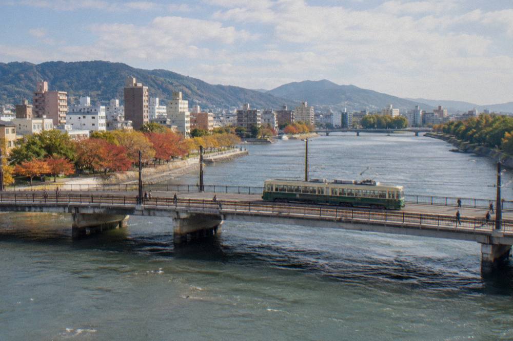 The Hiroden streetcar crossing a bridge above the Ota River in warm light