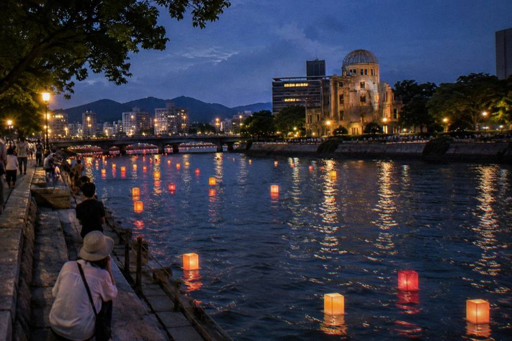 Paper lanterns floating on the Motoyasu River at dusk with the Atomic Bomb Dome in the background